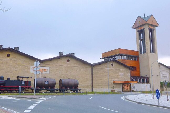 アロにあるボデガス・ムガの石造りの建物と樽を載せた展示列車